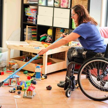 Person in wheelchair using rake to gather toys 