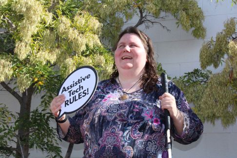Vision impaired AT Chat advocate holding a sign saying AT Rules 