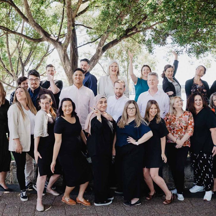 Group photo of the iLA team standing in front of a tree