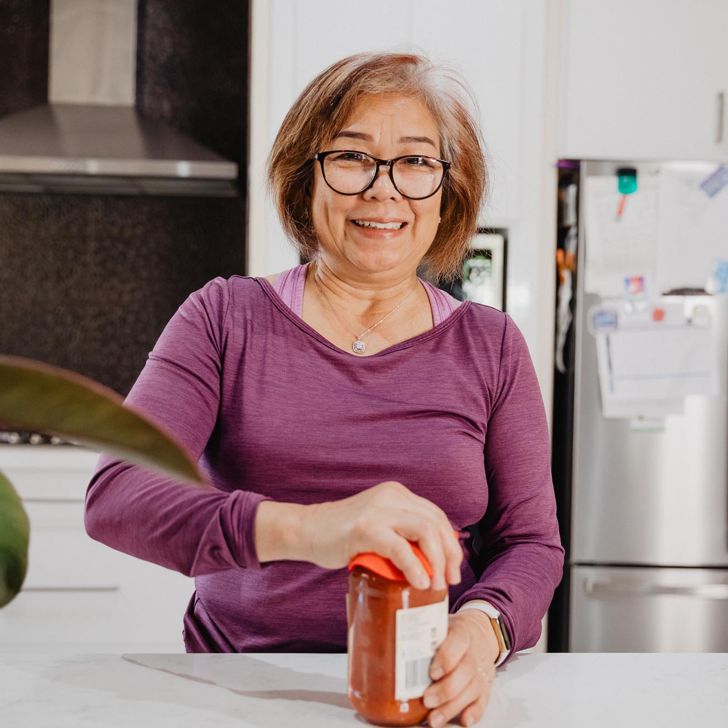 A senior woman using a jar opener to assist removing the lid