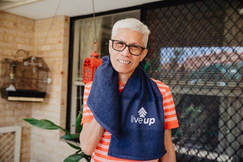 Older person outdoors holding towel with 'live up' logo