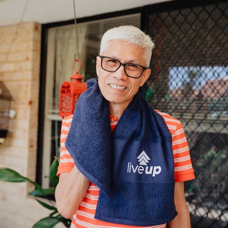 Older person outdoors holding towel with 'live up' logo