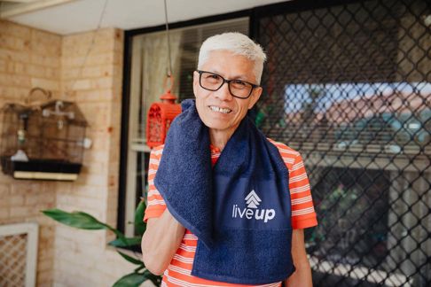 Older person outdoors holding towel with 'live up' logo