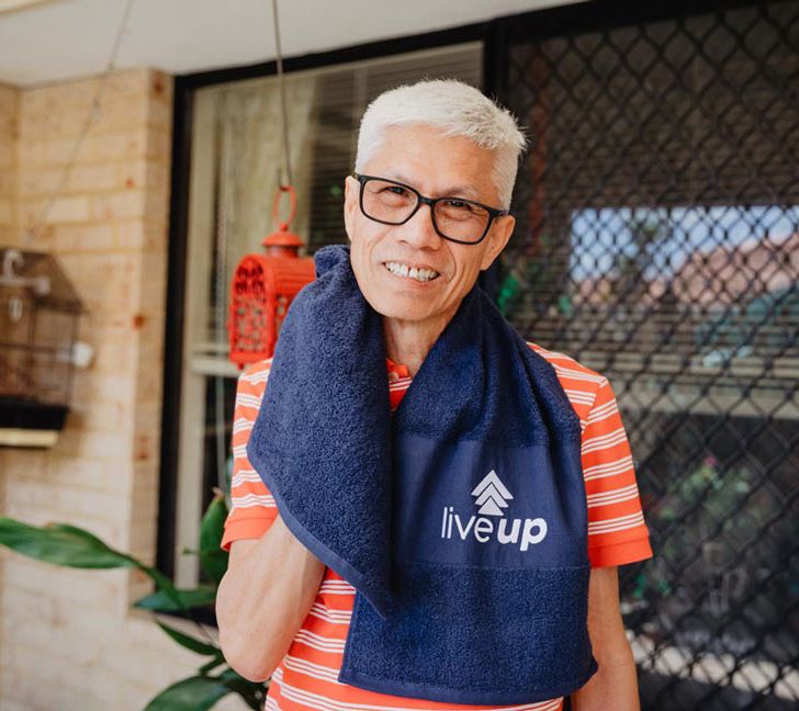 Older person outdoors holding towel with 'live up' logo