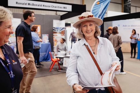 Woman wearing a hat holding a brochure smiling at the camera
