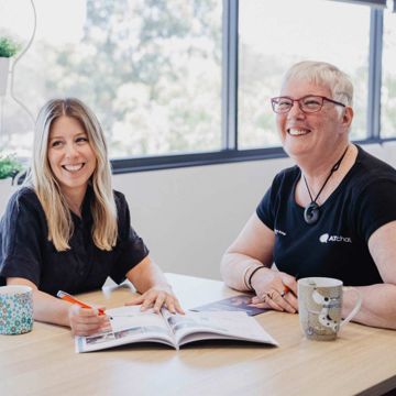 Two women from iLA smiling while discussing initiatives and looking through resources