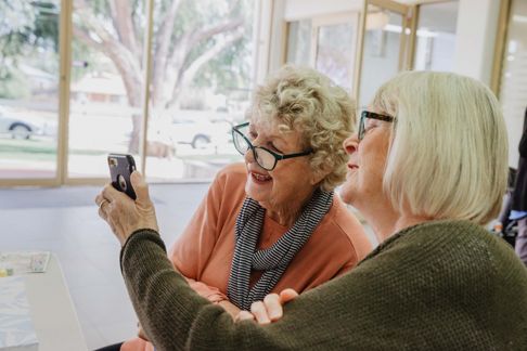 one woman showing another woman content on her mobile phone