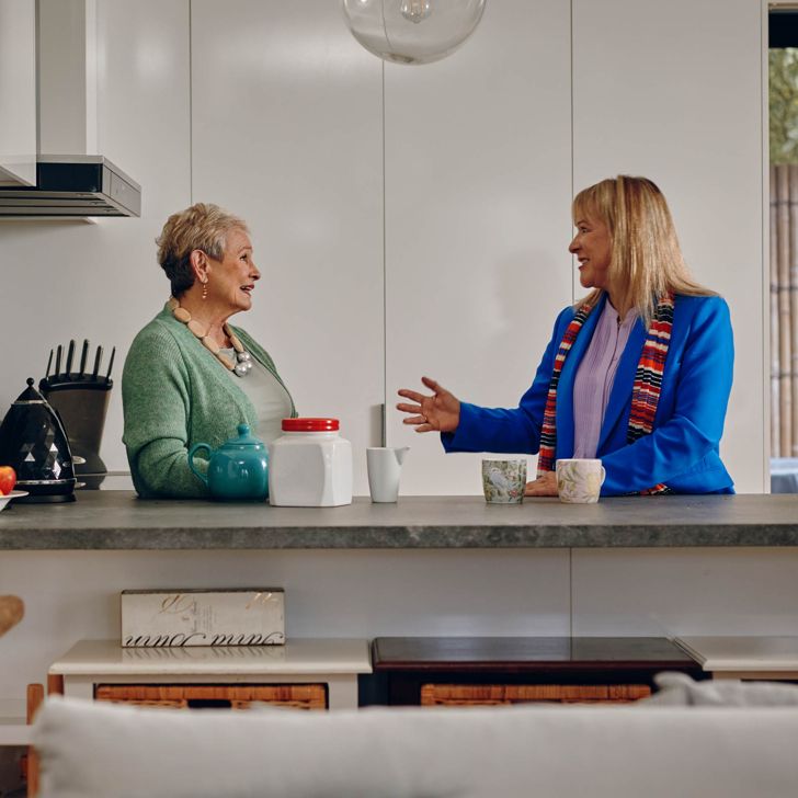 Two people talking at a kitchen counter 