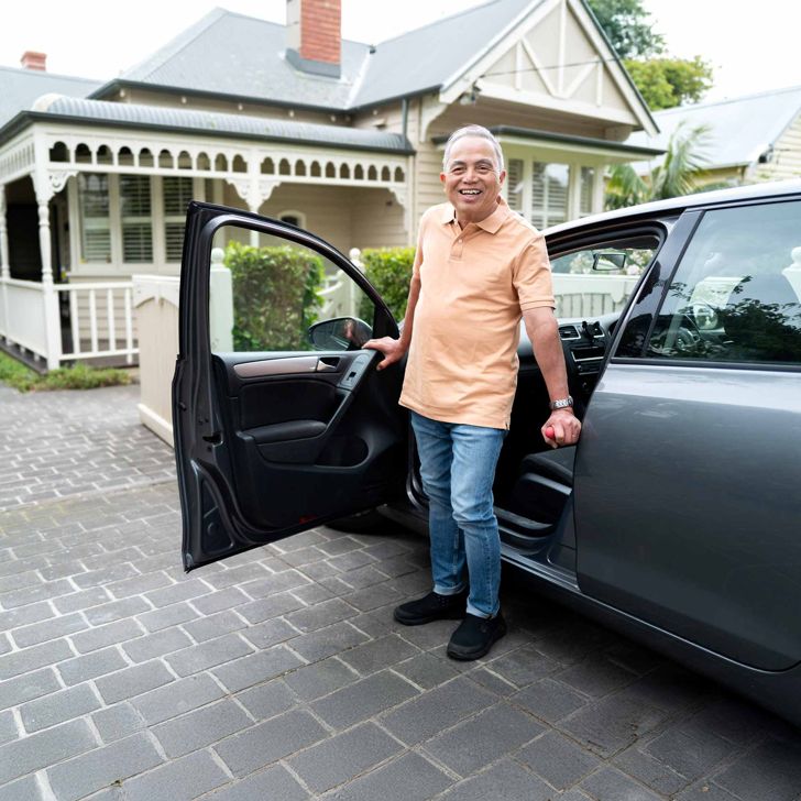 older man getting out of car using car bar