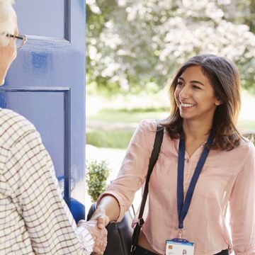 A support worker arriving at a clients home shaking hands at the front door