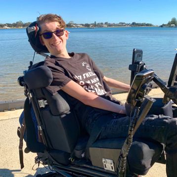 A man in a multi use wheelchair by a lake.