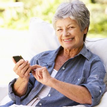 Elderly lady sitting in an armchair with mobile phone
