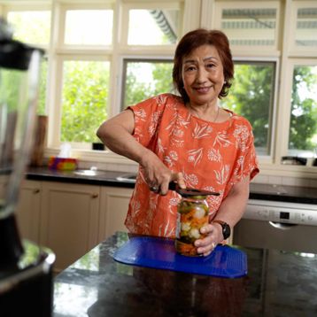  A senior lady using a jar opener in her kitchen
