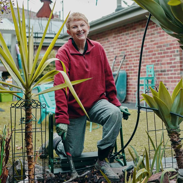 An older lady wearing gardening gloves doing a bit of gardening