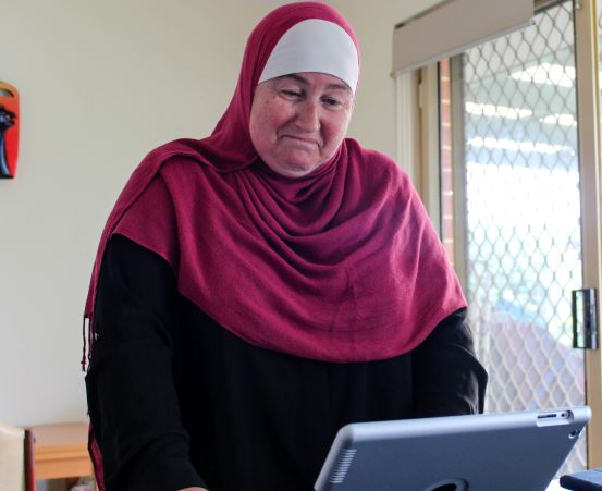 A woman wearing a hijab smiles at her computer