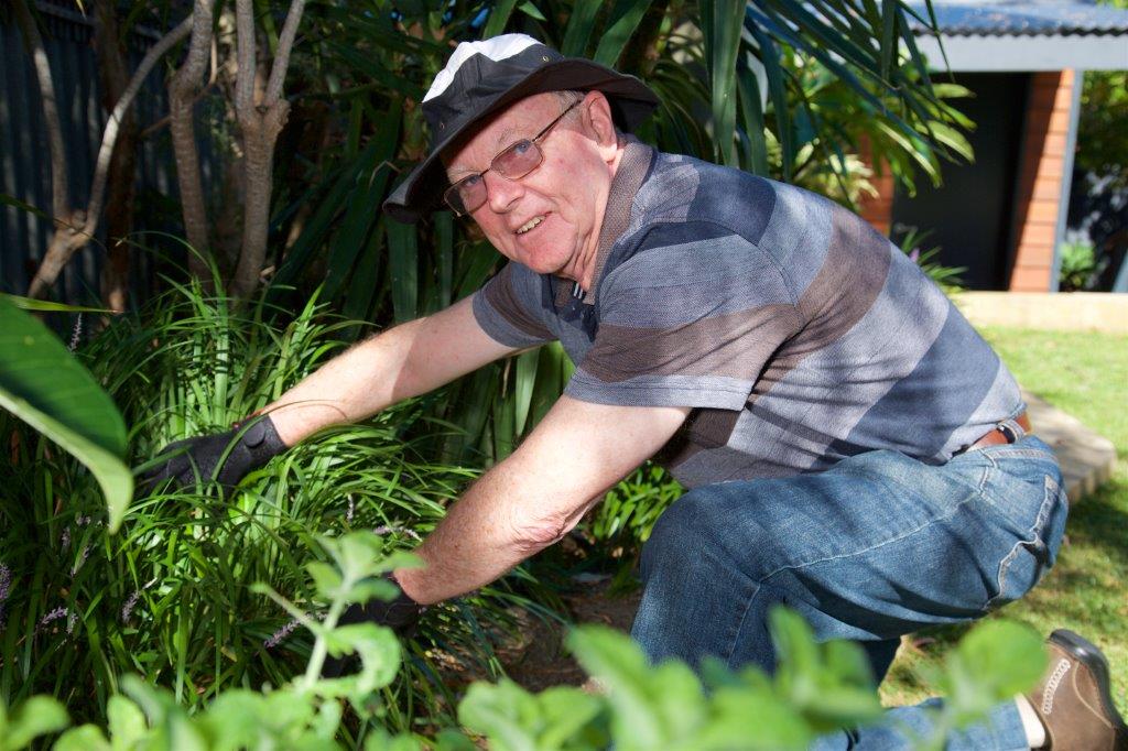 Male_Customer_Gardening Older male in blue shirt & glasses smiling watering garden
