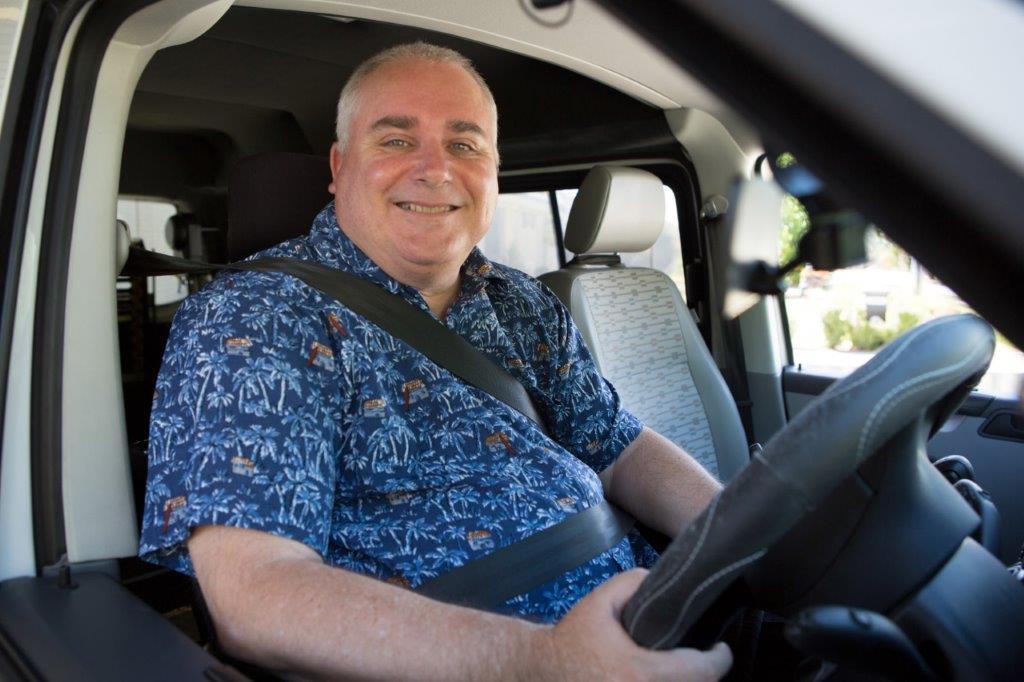 Man smiling in the driver's seat of a car