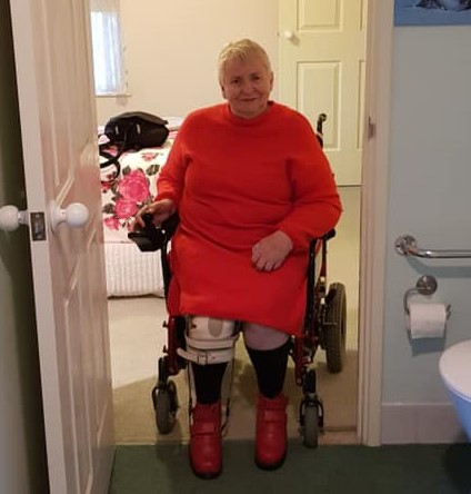 Female in red in a wheelchair positioned in the doorway of bathroom
