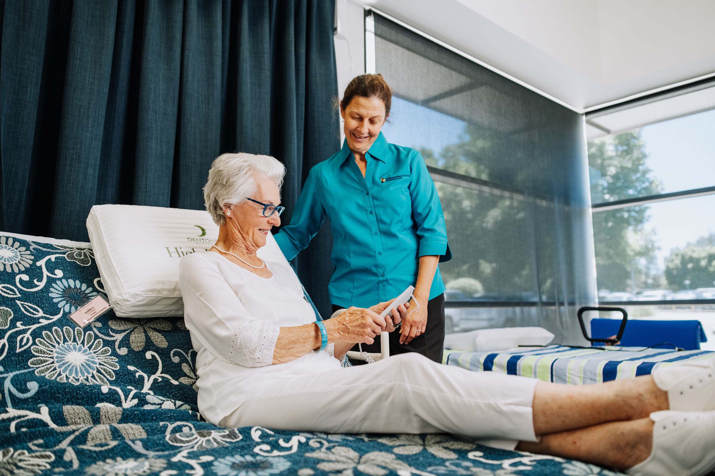Woman using an adjustable bed with the help of a care worker. Woman using an adjustable bed with the help of a care worker.