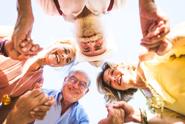 group-of-senior-people-bonding-outdoors-resize four older people holding hands in a circle