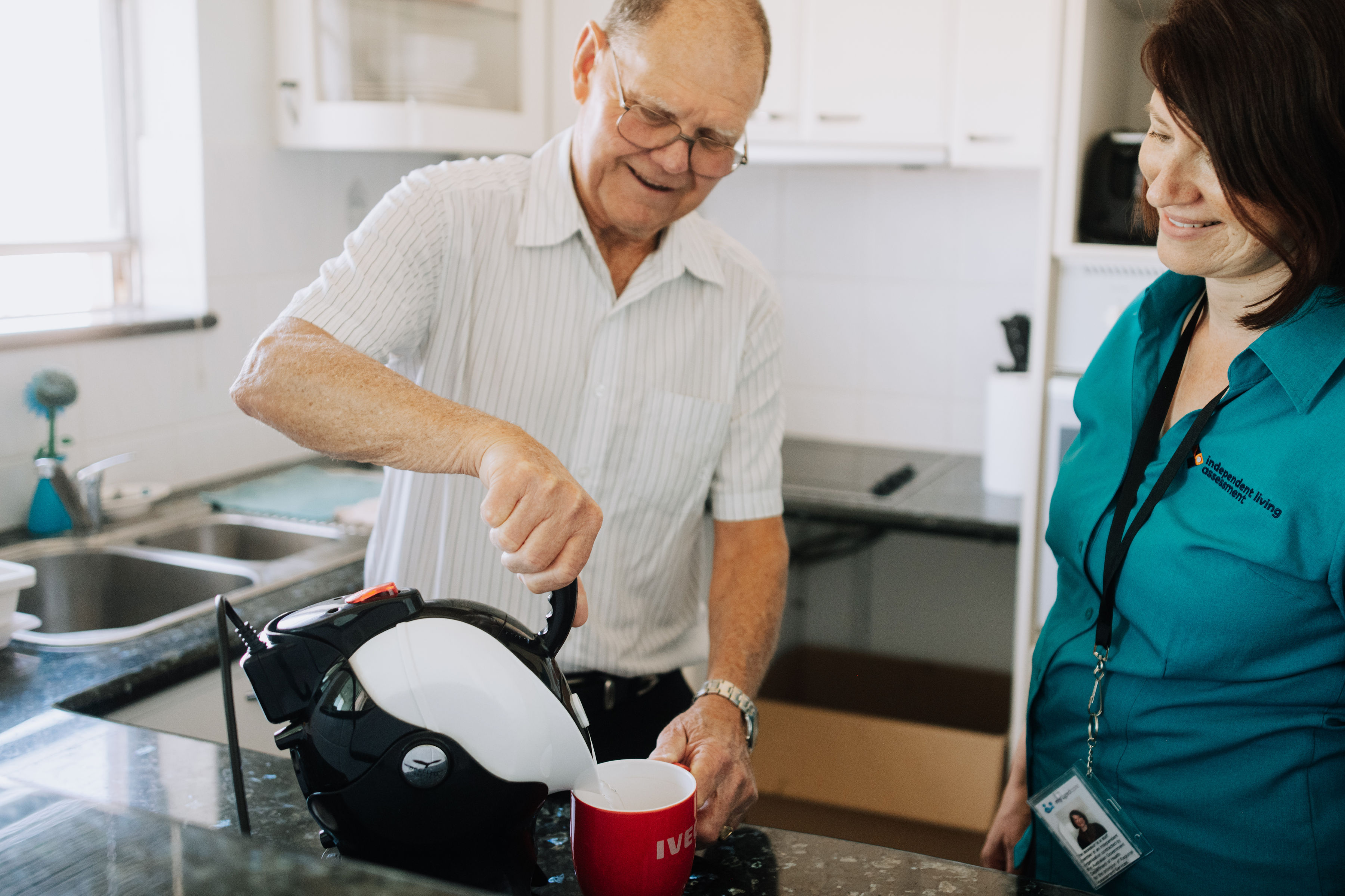 A man looks at a screen and works A woman is standing beside a man as he uses a tipper kettle