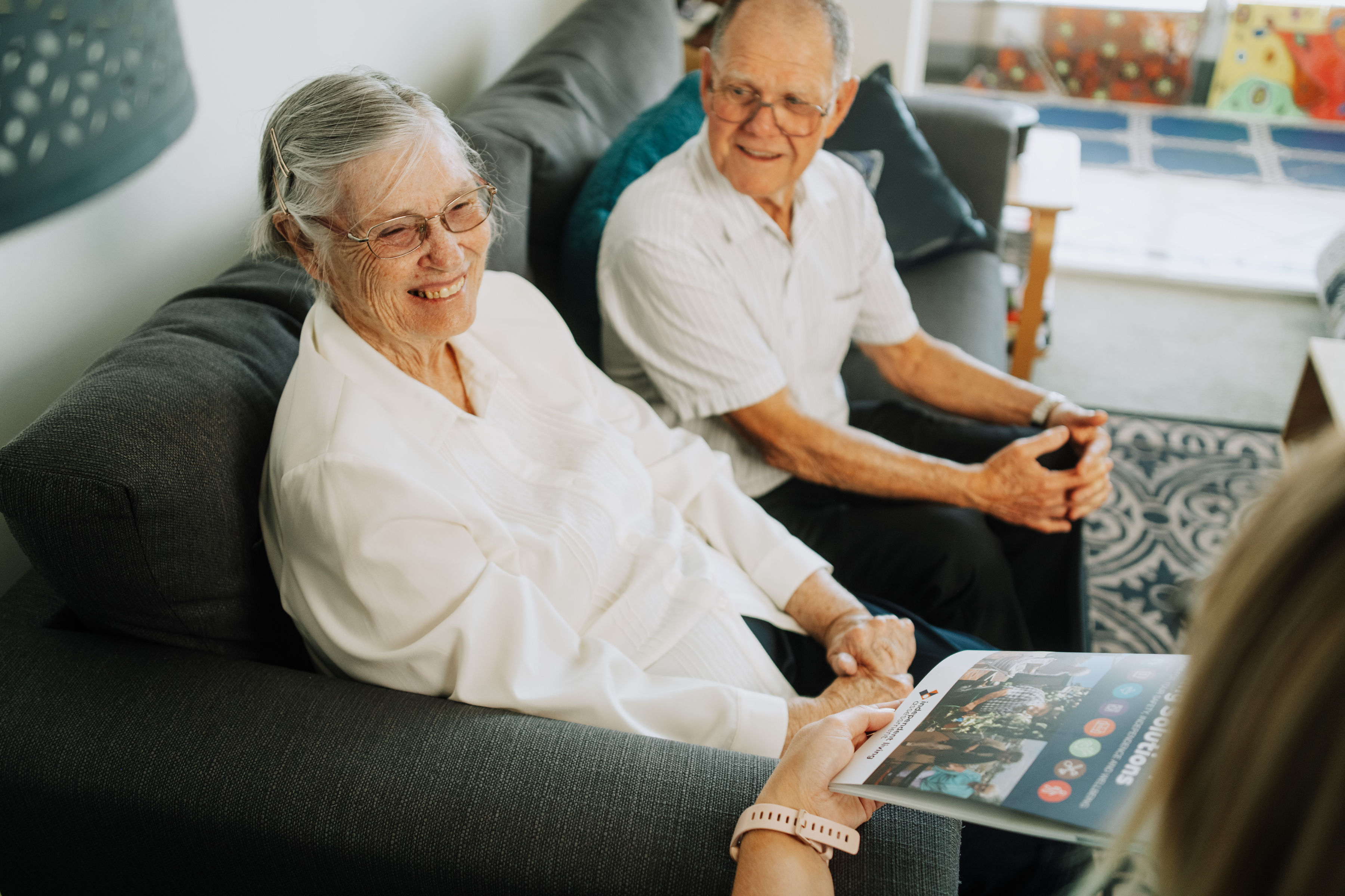 An older man and woman smile as they sit alongside each other at an assessment.